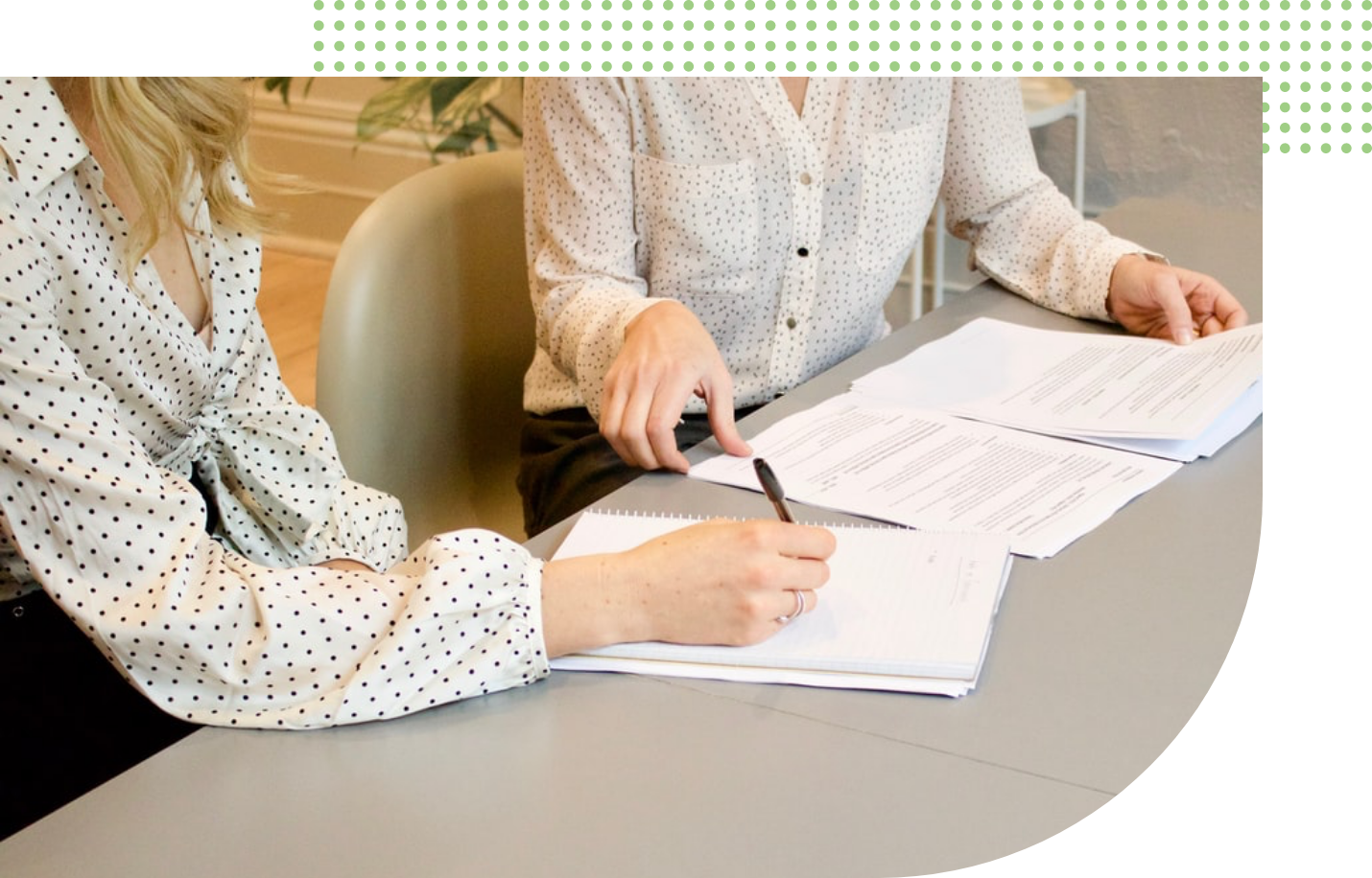 two people sitting down looking at sheets of paper on a desk 