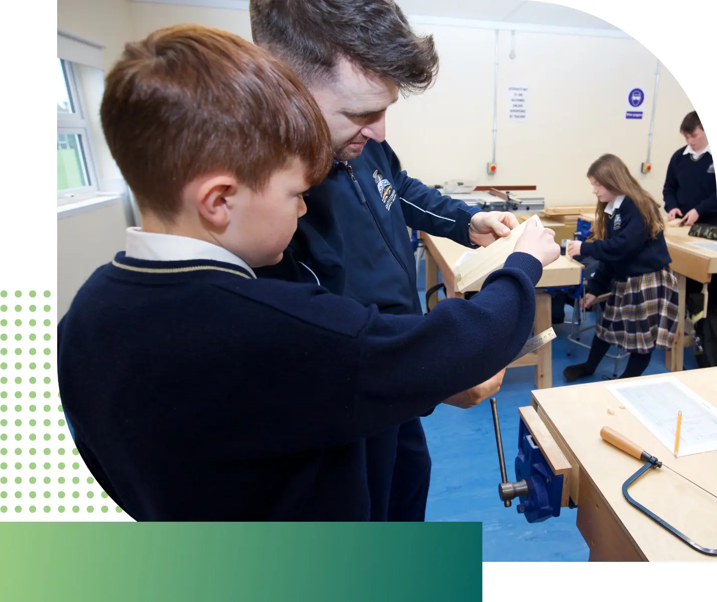 a woodwork teacher helping a student in the woodwork classroom