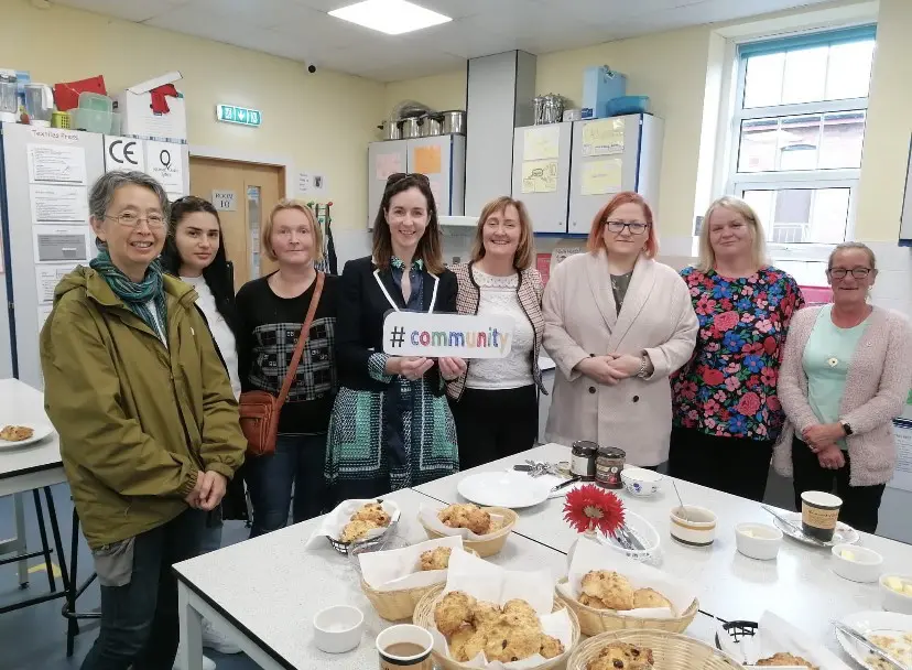 teachers and coordinators of Curragh Community College in the home economics room with scones and tea on a table in front of them 