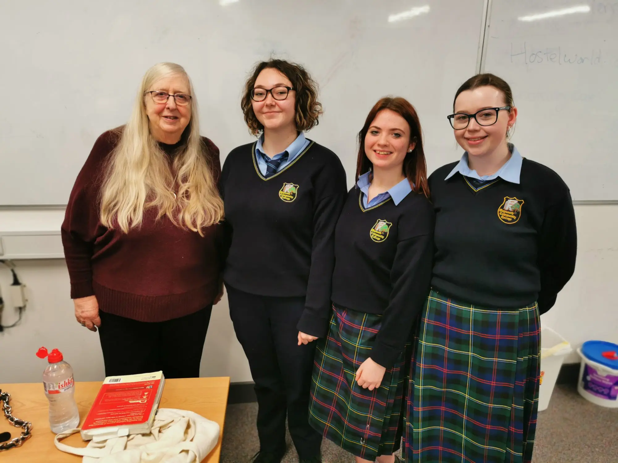 Maynooth Community College students standing with Leaving Cert Poet, Eiléan Ní Chuilleanáin in a classroom 