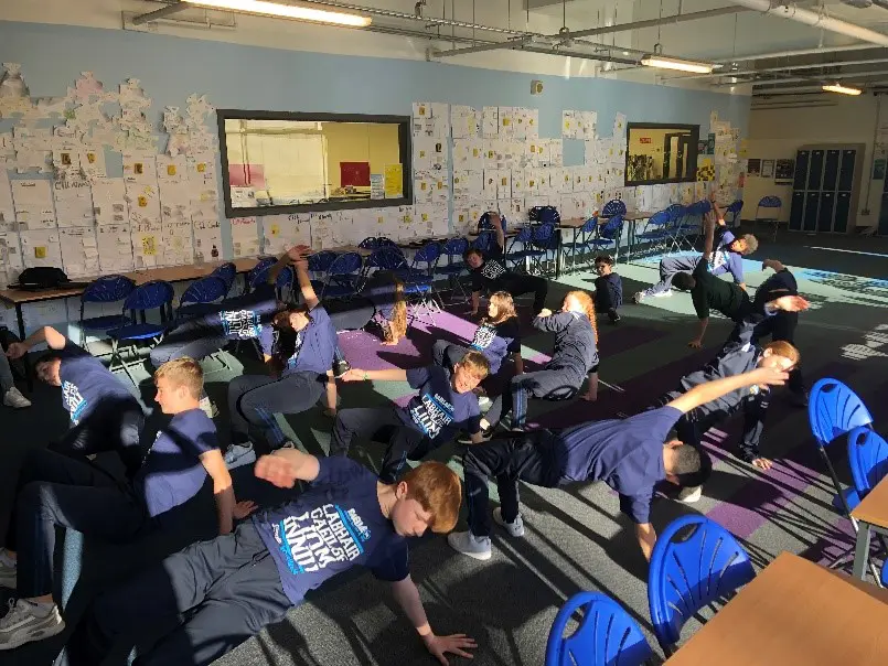 Gaelcholáiste Mhaigh Nuad students doing yoga in a classroom as part of celebrating the theme of the day - wellbeing 