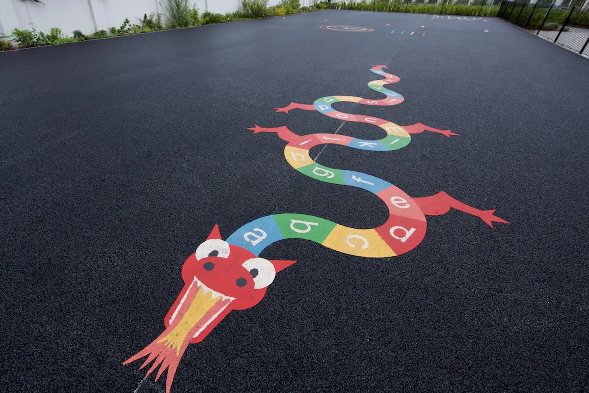 Colourful snake drawing on outdoor play area with the alphabet on it's body