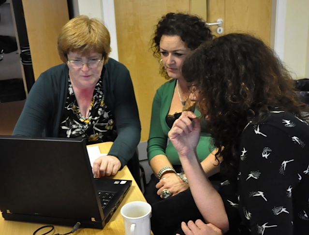 a group of three viewing a laptop screen