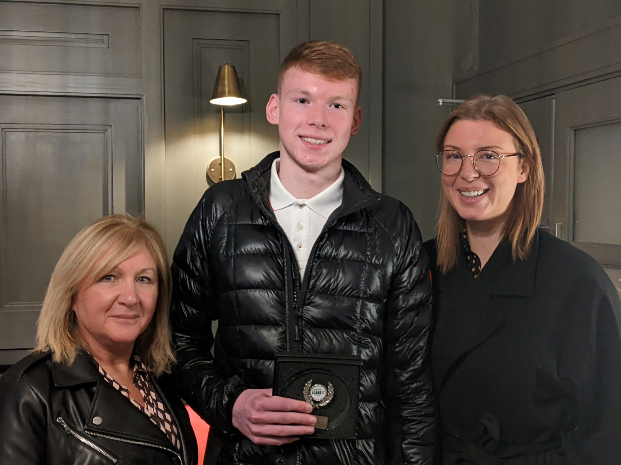 Confey College student standing with his mom and nan holding his award for getting 100% in his Leaving Cert Applied exam. 